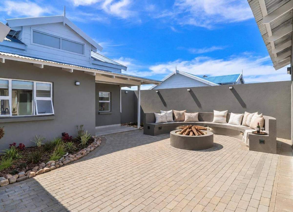 Outdoor courtyard with circular fire pit and built-in seating at ONPOINT27 Pinnacle Point Lodge, Mossel Bay
